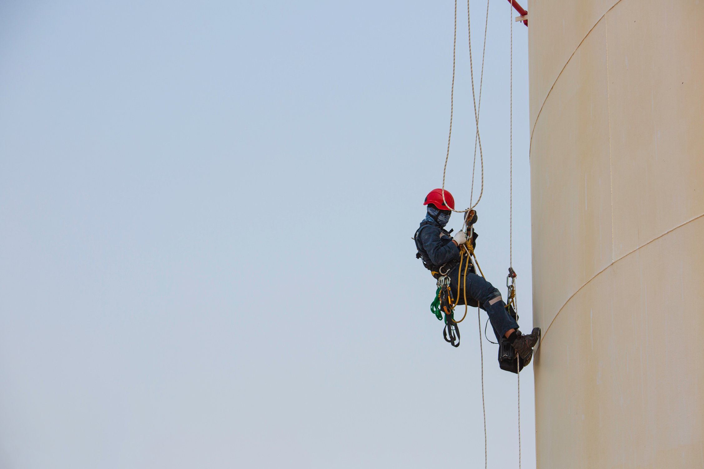 Male worker rope access industrial working at height tank oil we